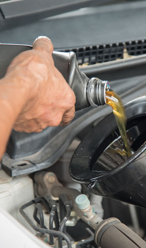 A person pouring oil into an engine.